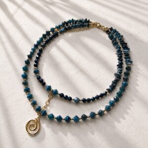 Colier dublu albastru cu pandantiv spirala este realizat manual din Apatit si Lapis Lazuli, in doua layere echilibrate. Primul layer are 39 cm, iar al doilea 42 cm, pentru o asezare clara la baza gatului. Lantul oval central tine cele doua coliere la distanta si sustine pandantivul tip spirala. Inchiderea este din Argint 925 aurit, iar detaliile metalice dintre pietre sunt placate cu Aur de 14K. Designul combina tonuri albastre profunde cu accente aurii si o structura usor de purtat.